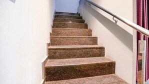 A staircase with granite steps and a metal handrail, leading to a landing with a door. - Cozy Inn T2 Mumbai Airport (Mumbai)