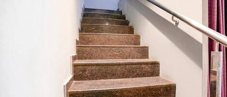Una escalera de piedra con barandilla de metal que conduce a un rellano con una puerta.