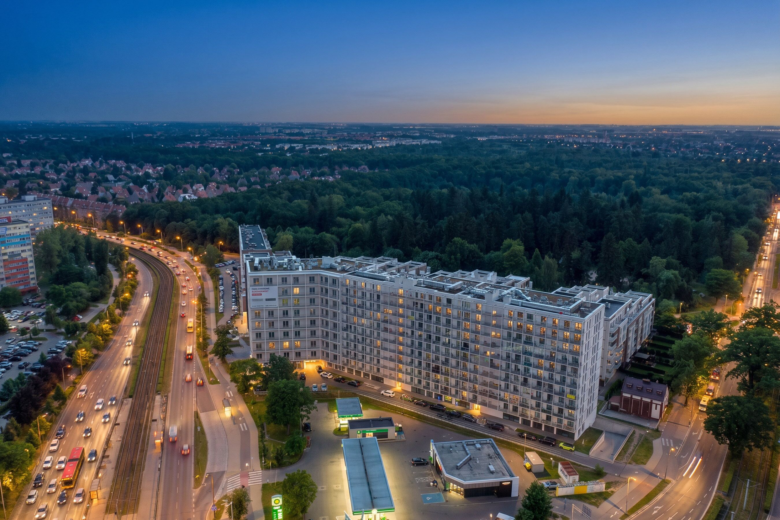 A multi-story hotel with a modern design, located near a highway and surrounded by greenery.