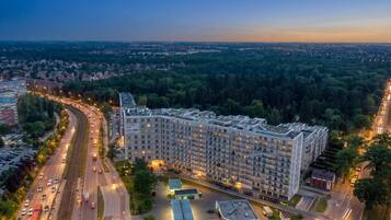A multi-story hotel with a modern design, located near a highway and surrounded by greenery.