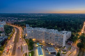A multi-story hotel with a modern design, located near a highway and surrounded by greenery.