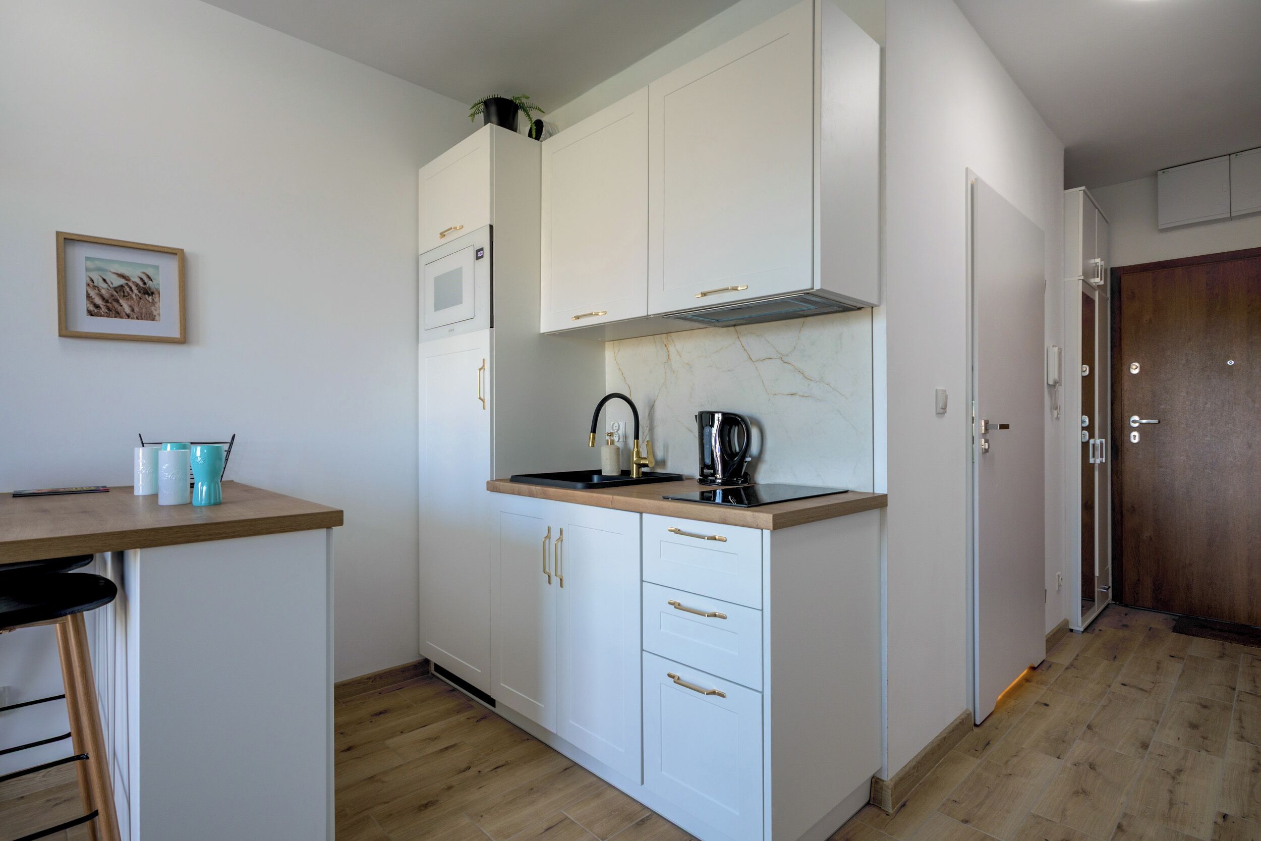 A compact kitchen with white cabinets, a microwave, and a coffee maker.