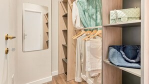 A walk-in closet with wooden shelving, a hanging rod, and a door.