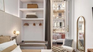 Une chambre d’hôtel comprenant un lit, une table de chevet, un miroir, une armoire et donnant sur un balcon aménagé avec du mobilier d’extérieur.