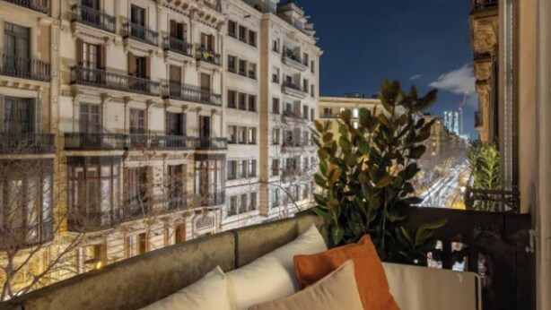 Un balcon offrant une vue sur une ville illuminée la nuit, avec des immeubles à plusieurs étages dotés de balcons.