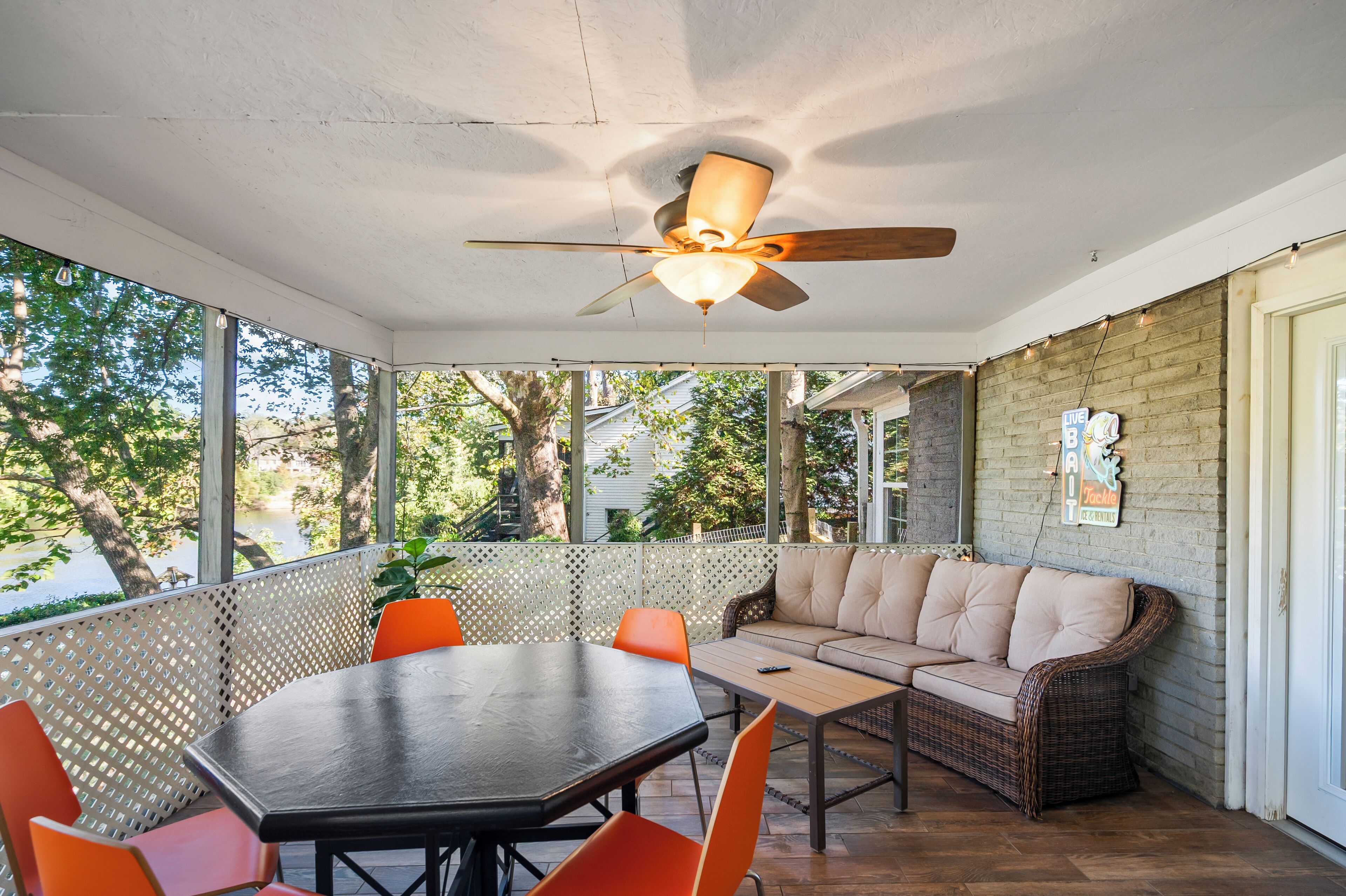 A covered patio area with a table and chairs, a sofa, and a ceiling fan.