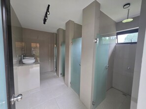 Un baño moderno con un lavamanos grande, una cabina de ducha de vidrio y una lámpara en el techo.