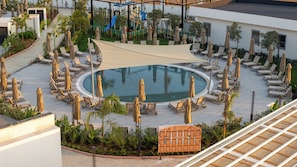 A pool area with lounge chairs and umbrellas, surrounded by greenery and a playground. - Raxeria Hotel - All Inclusive (Manavgat)