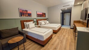 A hotel room with two beds, a sofa, a small table, and a TV.