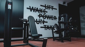 Uma academia com equipamentos de exercícios e frases motivacionais na parede.