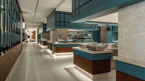 A modern hotel lobby with a long reception desk, a glass display case, and a seating area with tables.