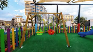 A children's play area with a swing set, colorful fence, and a slide.