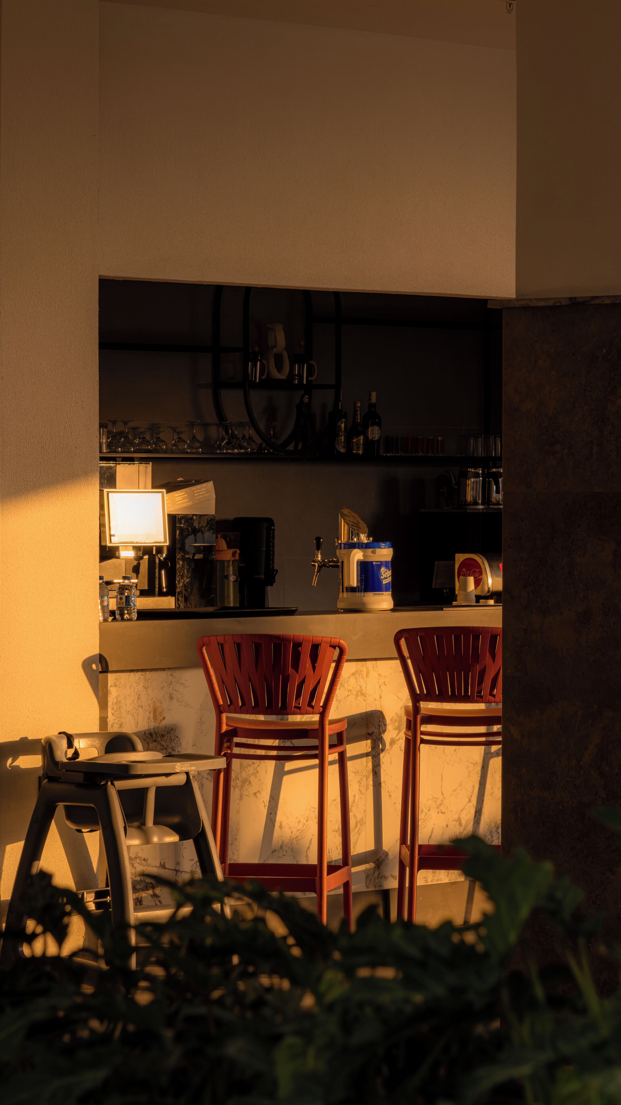 A bar area with two wooden chairs, a counter with a beer tap, and shelves with bottles and glasses.