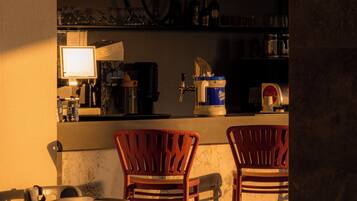 A bar area with two wooden chairs, a counter with a beer tap, and shelves with bottles and glasses.