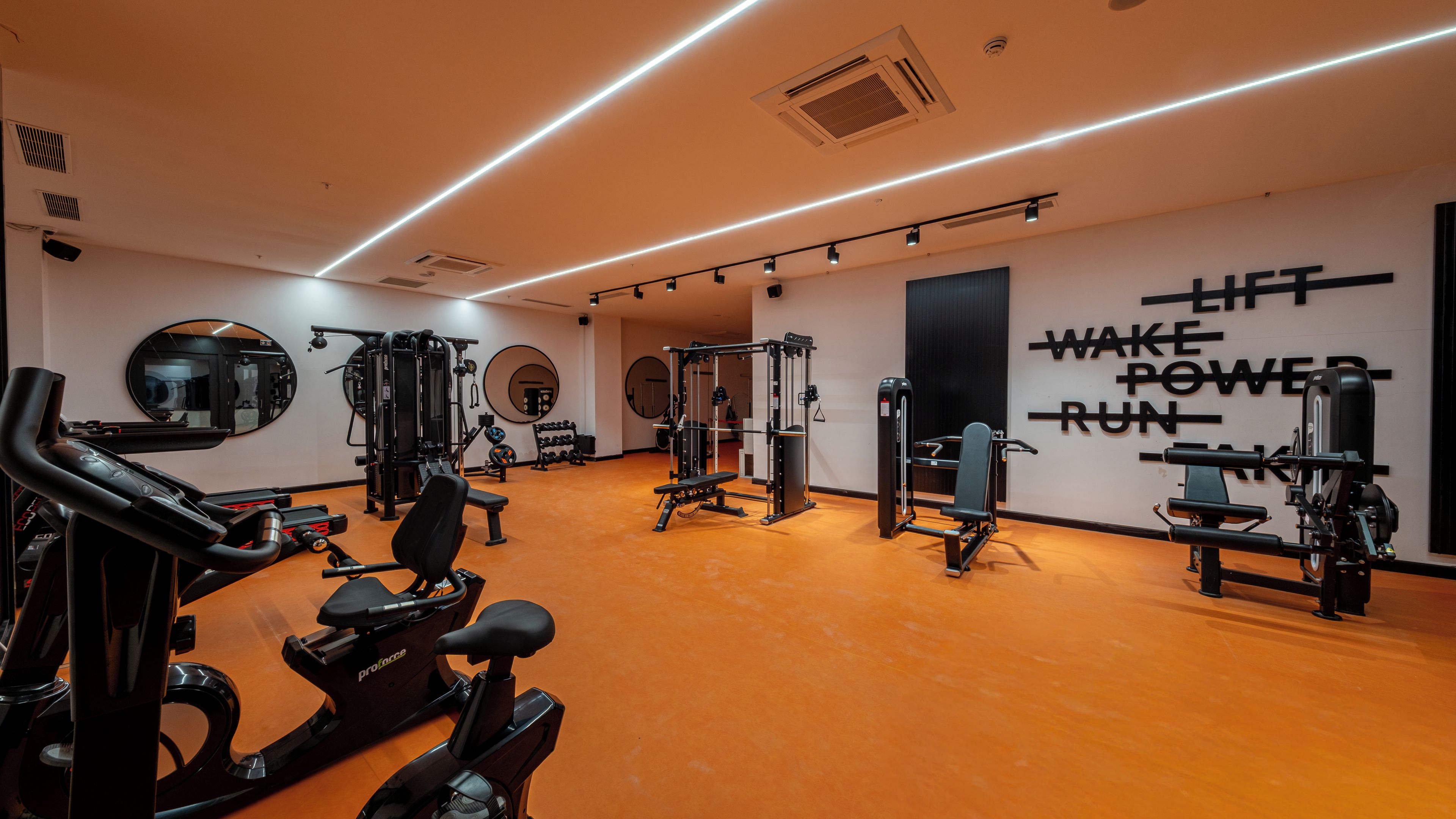 A gym with exercise equipment, mirrors, and motivational wall text.