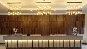 A reception area with a wooden panel wall, a reception desk, and a ceiling with recessed lighting and an air conditioning unit. - Raxeria Hotel - All Inclusive (Manavgat)