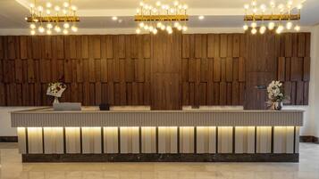 Un área de recepción con un panel de madera en la pared, un mostrador de recepción e iluminación empotrada en el techo, además de una unidad de aire acondicionado.