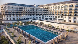Un hotel grande con piscina central rodeada de tumbonas y sombrillas.