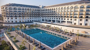 Un hotel grande con piscina central rodeada de tumbonas y sombrillas.