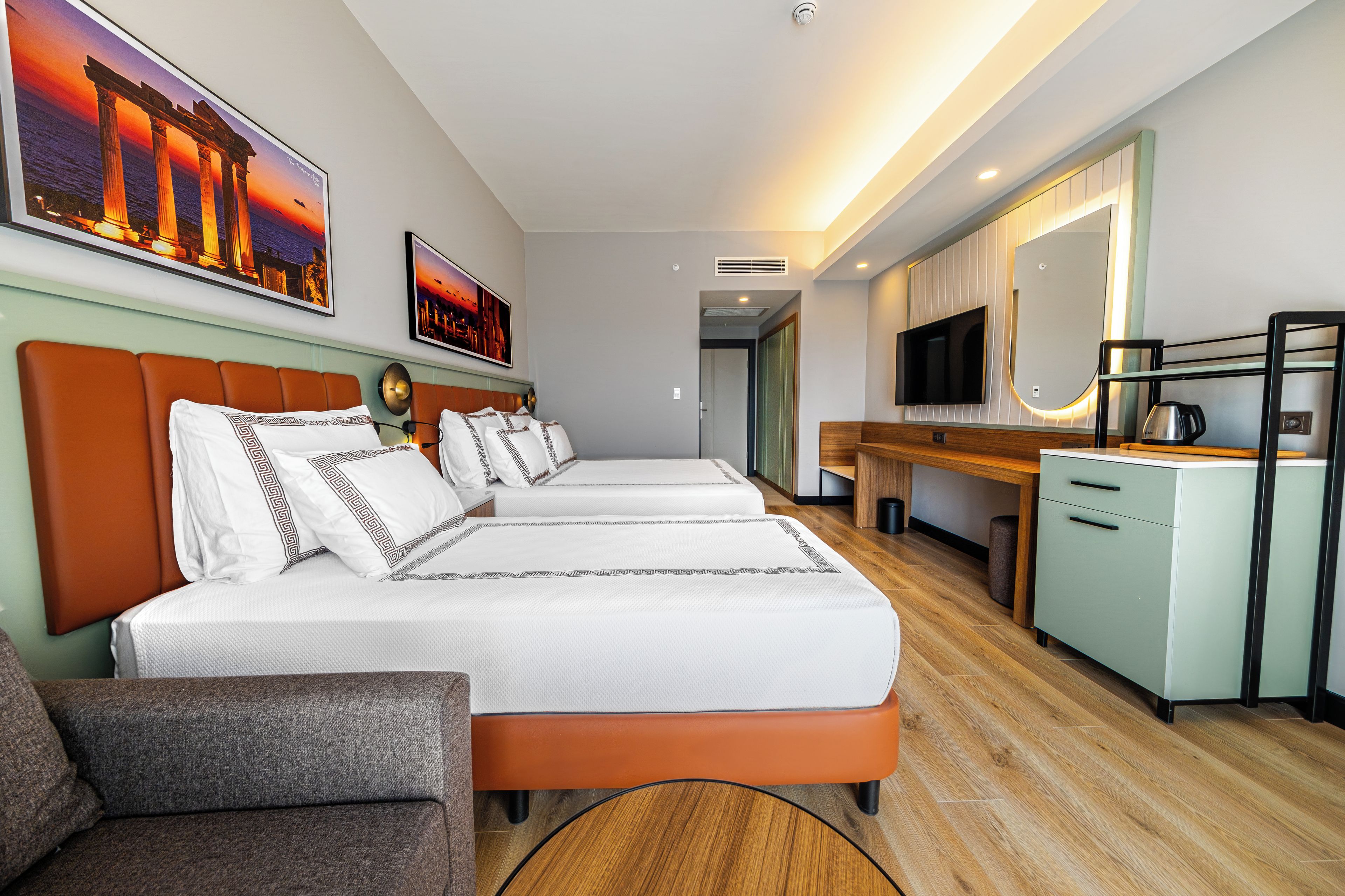 Habitación de hotel con dos camas, un escritorio, un televisor y una cafetera.