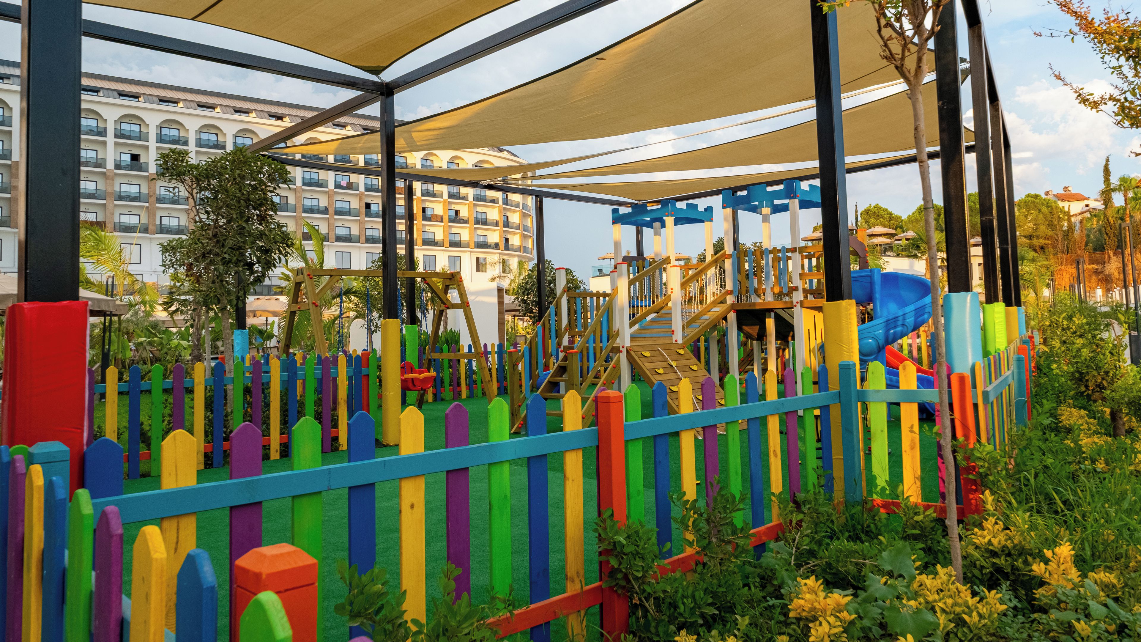 Un parque infantil con estructuras de juego coloridas y una zona de descanso cubierta.