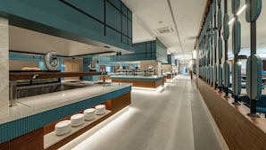 Una cocina moderna con una isla central, electrodomésticos de acero inoxidable y una encimera larga con platos apilados.