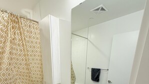 A modern bathroom with a white sink, a toilet, and a shower area.