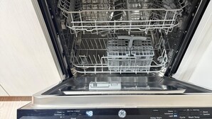 An open dishwasher with multiple racks and a control panel displaying various settings.