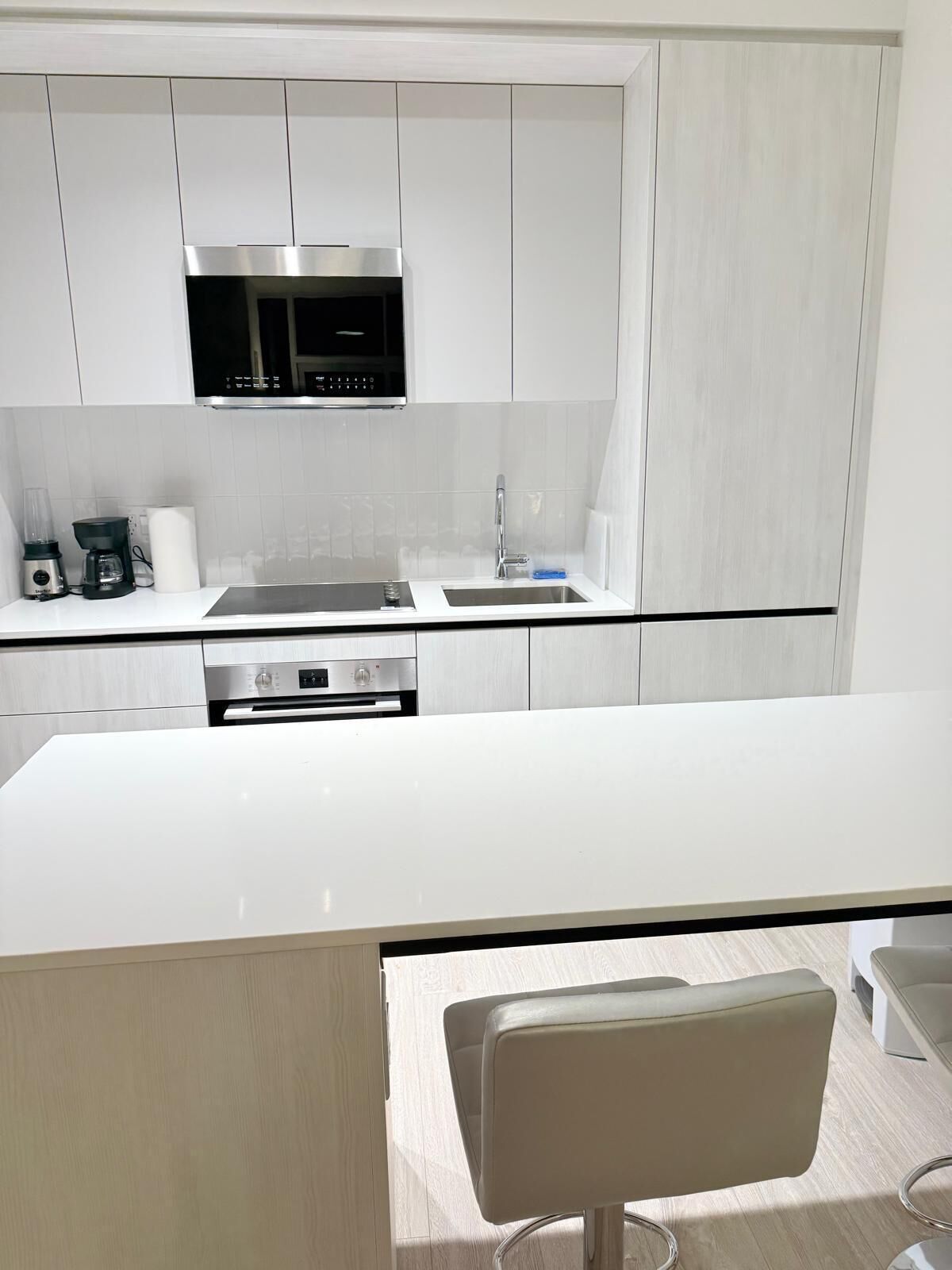 Cocina moderna con armarios blancos, electrodomésticos de acero inoxidable y una isla central.