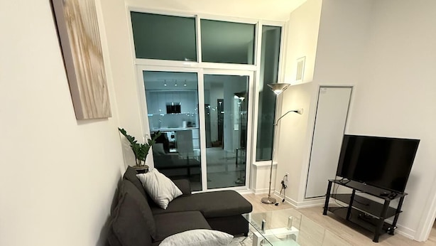 A modern living room with a sofa, coffee table, lamp, and TV.
