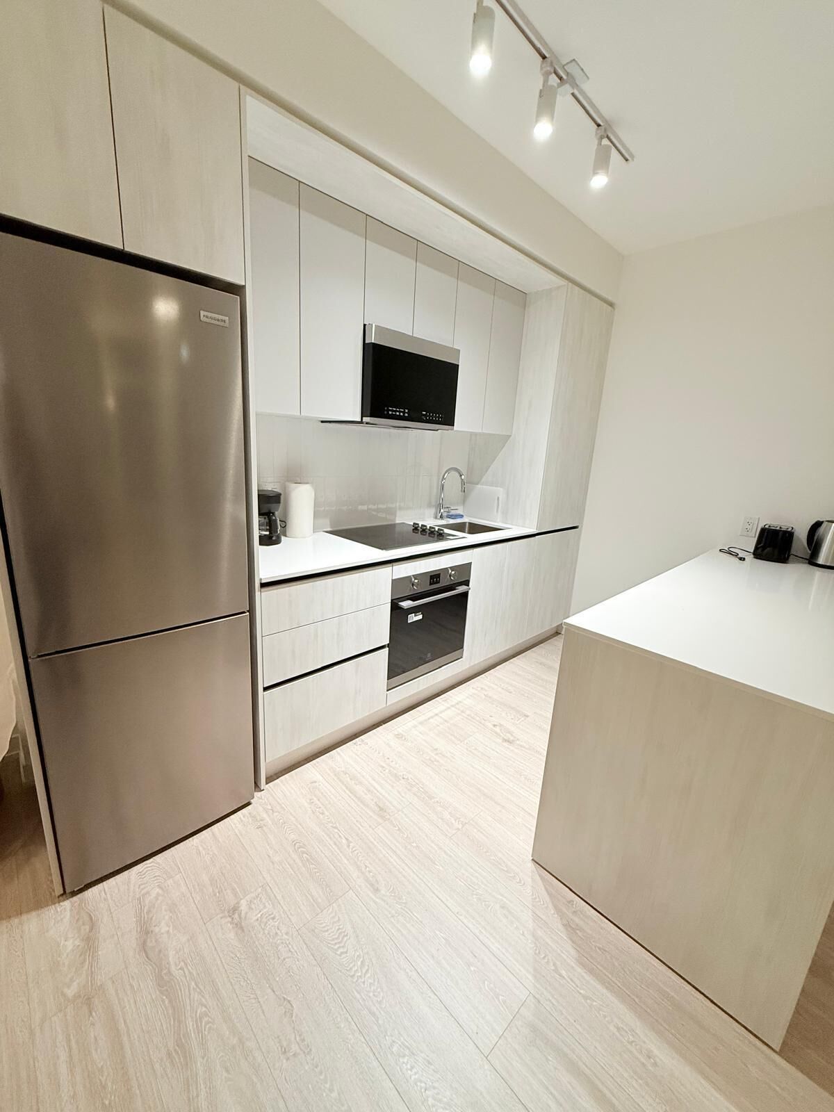 A modern kitchen with a stainless steel refrigerator, a built-in oven, and a microwave.