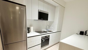 A modern kitchen with a stainless steel refrigerator, a built-in oven, and a microwave.