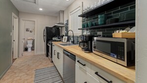 A compact kitchen with a dishwasher, a coffee maker, and a microwave. - Gothic Garden Bright, Cozy Escape with Modern Touches in Historic Bryan (Bryan)