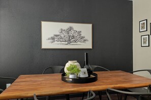 Une table à manger sur laquelle se trouve un plateau contenant un vase, une tasse et une petite plante.