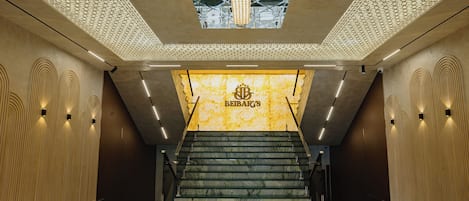 A modern interior with a staircase leading to a reception area labeled 'BIBARY'S'.
