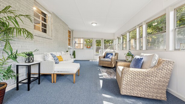 A spacious living area with a white brick wall, large windows, and comfortable seating.
