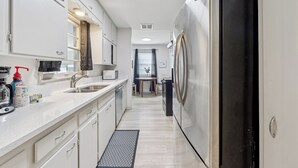 A modern kitchen with white cabinetry, a stainless steel refrigerator, a microwave, and a coffee maker on the counter.