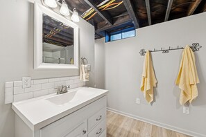 Une salle de bain avec un lavabo blanc, un miroir et deux serviettes suspendues à un porte-serviettes en métal.