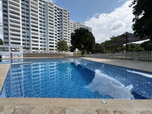 A swimming pool with a tiled deck, surrounded by a fence and trees. - Cozy apartment, nice view, air conditioning, three blocks from the park. (Santa Fé de Antioquia)