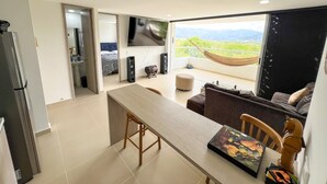 Een moderne keuken met een groot eiland, een zithoek met een bank en uitzicht op bergen door grote ramen.