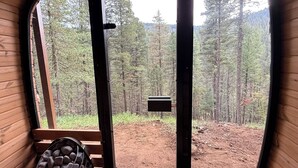 A wooden cabin interior with a large window revealing a forest view. - Cloudcroft Hideaway - No Neighbors, Just Nature! Modern Cabin Vibe and SAUNA! (Cloudcroft)