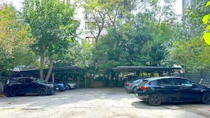 Un espace de stationnement avec plusieurs voitures, des arbres et une structure abritée.
