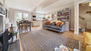 Een ruime woonkamer met een bank, een eettafel en een keuken op de achtergrond.