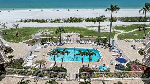 Un resort con piscina, spiaggia e palme.