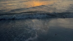 Un tramonto sul mare calmo, con onde leggere.