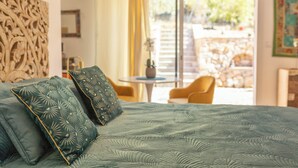 Een slaapkamer met een bed, twee kussens, een nachtkastje, een raam en uitzicht op een terras.