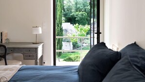 Un dormitorio con una cama, un escritorio y una ventana con vistas a un jardín.
