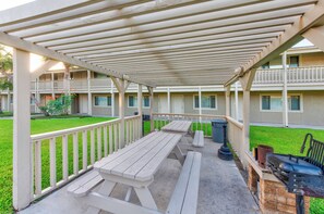 A covered outdoor area with picnic tables and a barbecue grill.