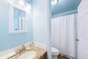 A bathroom with a sink, mirror, and shower curtain.