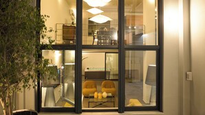 Un interior moderno con puerta de vidrio, zona de comedor con sillas amarillas y una bañera de hidromasaje visible.